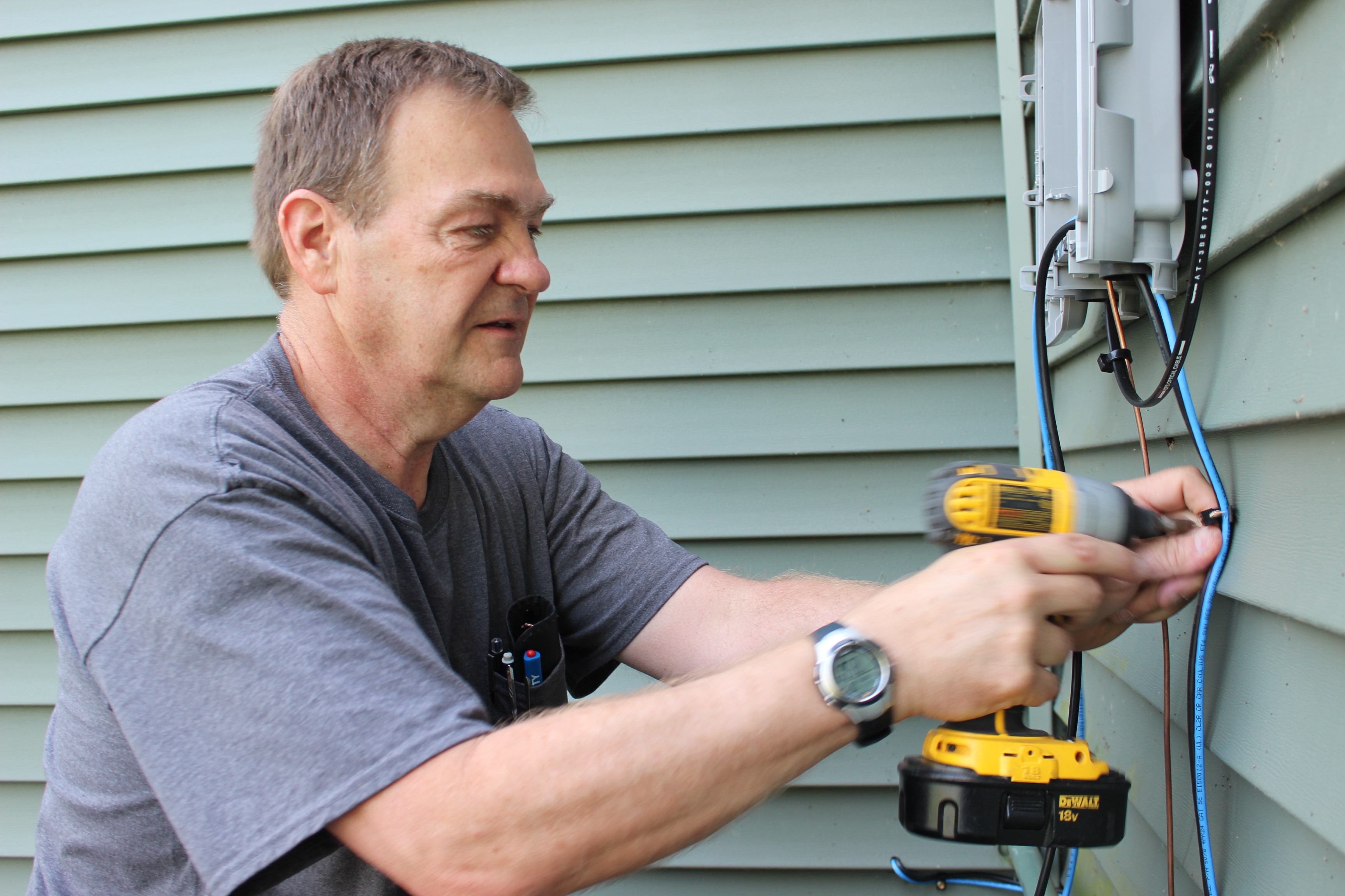 Fiber technician Gary Martin installs outdoor ONT onto a home.