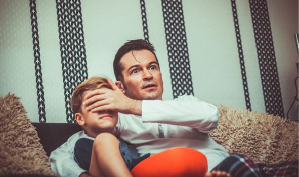 Dad blocking son's eyes from TV